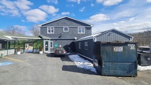 Ett motell med en parkeringsplats, ett överbyggt väntområde och en container märkt med texten ”KOMMUNALT AVFALL”.