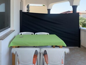 A patio area with a table and chairs, a black privacy screen, and a window. - Apartment Vir 5 (Vir)