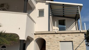 A modern two-story building with a stone facade, a balcony with metal railings, and a staircase leading to the upper floor. - Apartment Vir 5 (Vir)