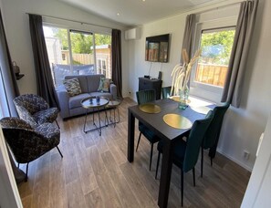 A modern living room with a sofa, coffee table, dining table with chairs, and a TV on the wall. - Beachside Chalet Near De Pluimpot for 4 (Scherpenisse)