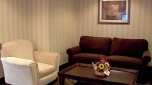 A room with a beige armchair, a brown sofa, and a coffee table with a floral arrangement.
