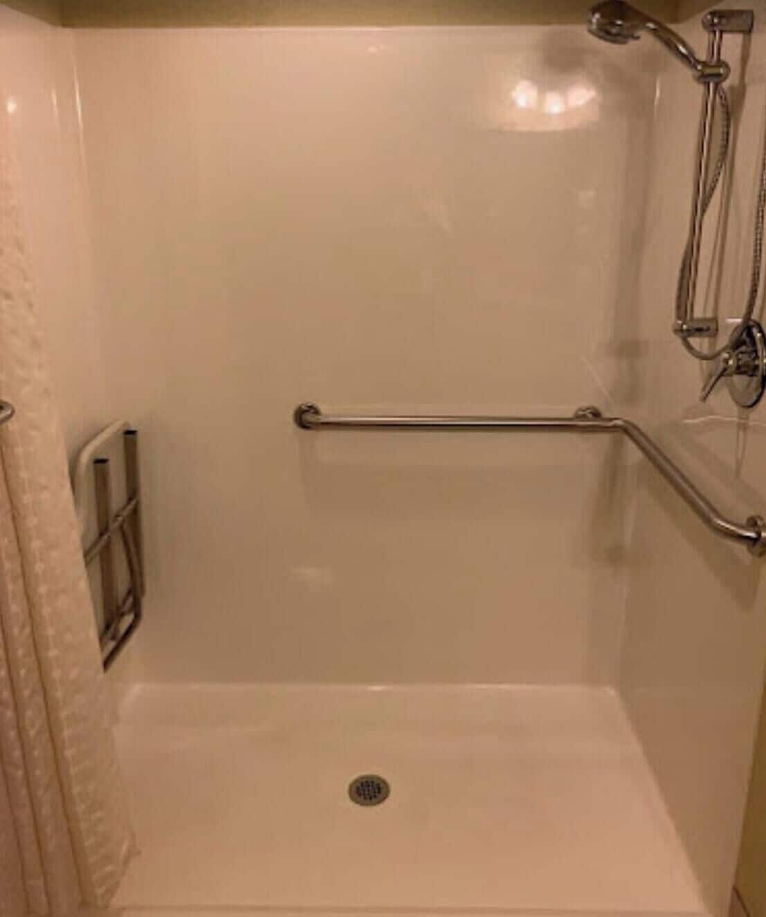 Een douche met een greep, een afvoer en een handdoekhouder.