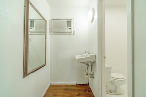 Een kleine badkamer met een witte wastafel, spiegel en toilet.