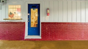 Un edificio con una porta blu, un estintore fissato al muro e una finestra con la bandiera americana.