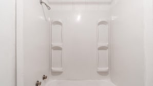 Un bagno bianco con una vasca, due soffioni doccia e un water.