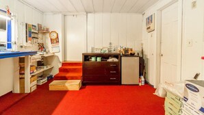 Una habitación con un escritorio, estanterías, un reloj, un mueble pequeño y una puerta.