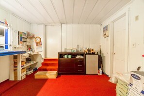 A room with a desk, shelves, a clock, a small cabinet, and a door.