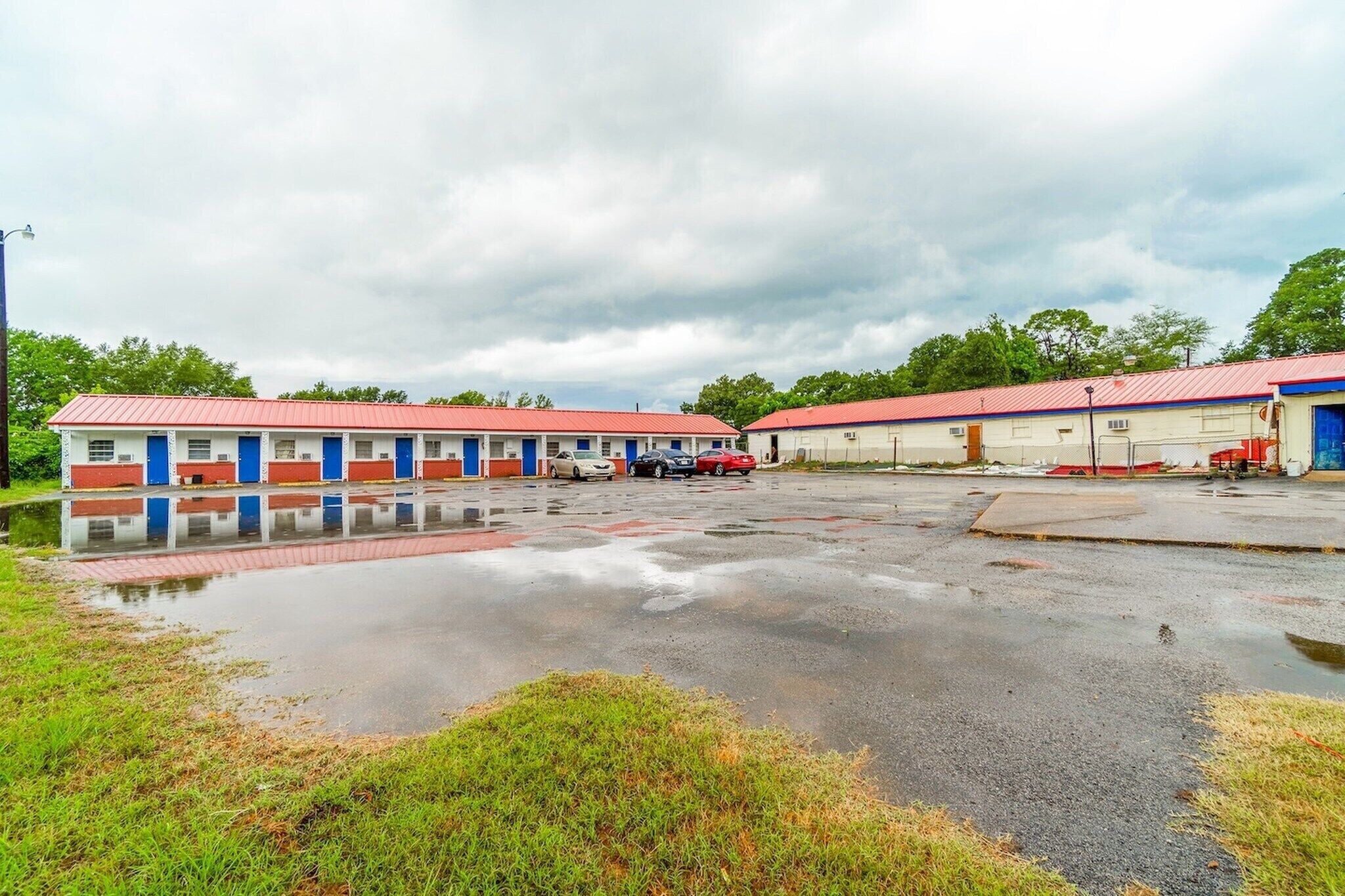 A motel with multiple rooms, a parking lot, and a small body of water reflecting the buildings.