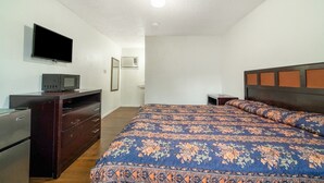 Une chambre à coucher avec un lit, une télévision, une commode et un four à micro-ondes.