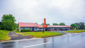 Un motel avec un toit rouge et une enseigne haute.