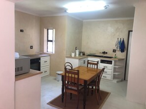 Una cocina compacta con una mesa de comedor, sillas, un refrigerador y una ventana.