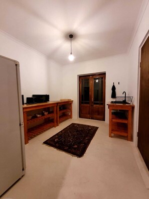 Una habitación con un armario de madera, un tapete, una puerta y una lámpara en el techo.