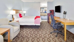 Una habitación de hotel con una cama, un escritorio, una silla, un televisor y un teléfono.