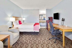 A hotel room with a bed, a desk, a chair, a TV, and a phone. - Cape Coral FL | King bed (Ingleside TX)