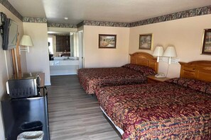 A hotel room with two beds, a television, a refrigerator, and a bathroom visible through an open door.