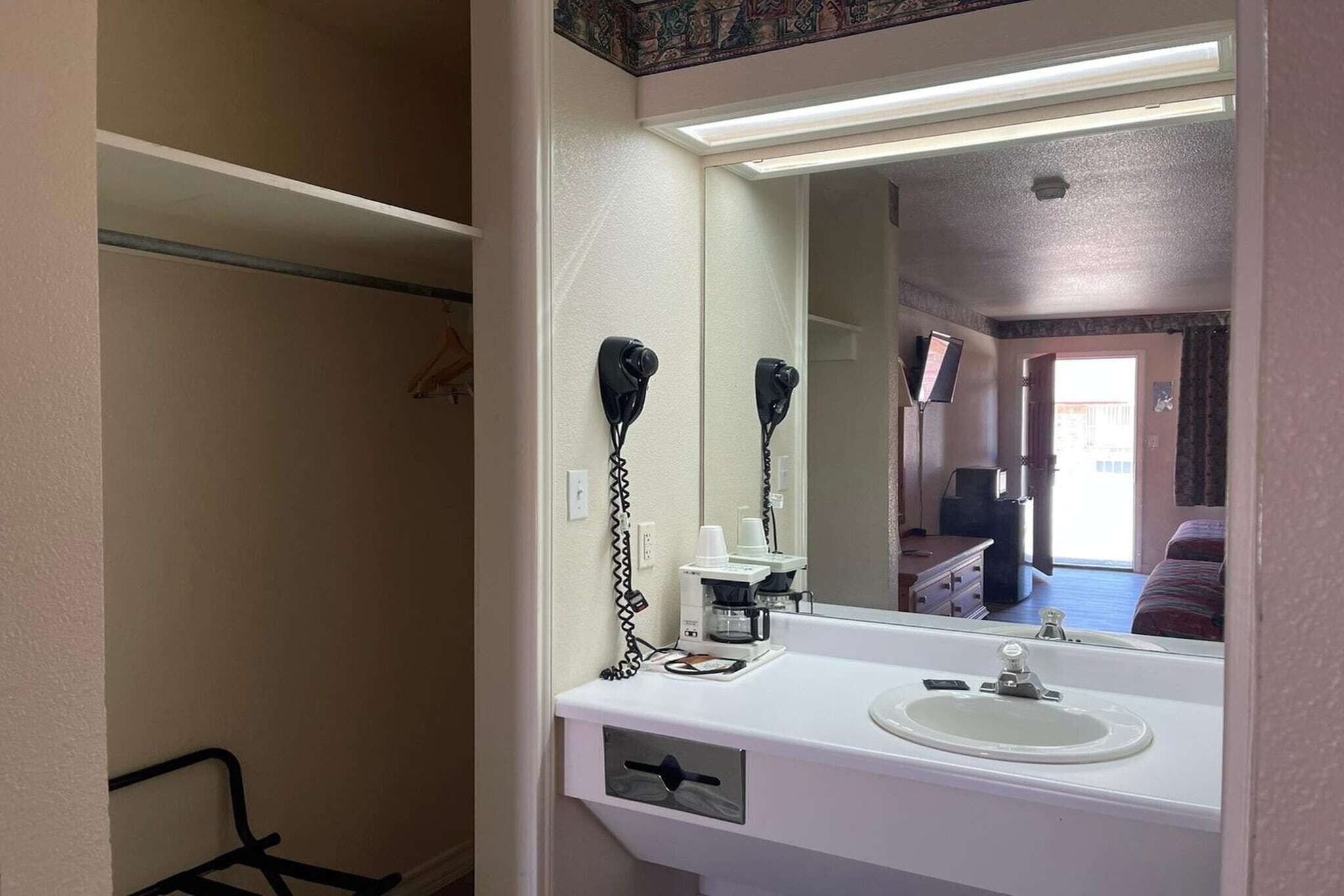 A bathroom with a white sink, a mirror, and a hairdryer.