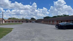 A motel with a central parking area, a row of rooms on one side, and a row of rooms on the other side.