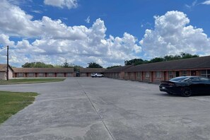 A motel with a central parking area, a row of rooms on one side, and a row of rooms on the other side.