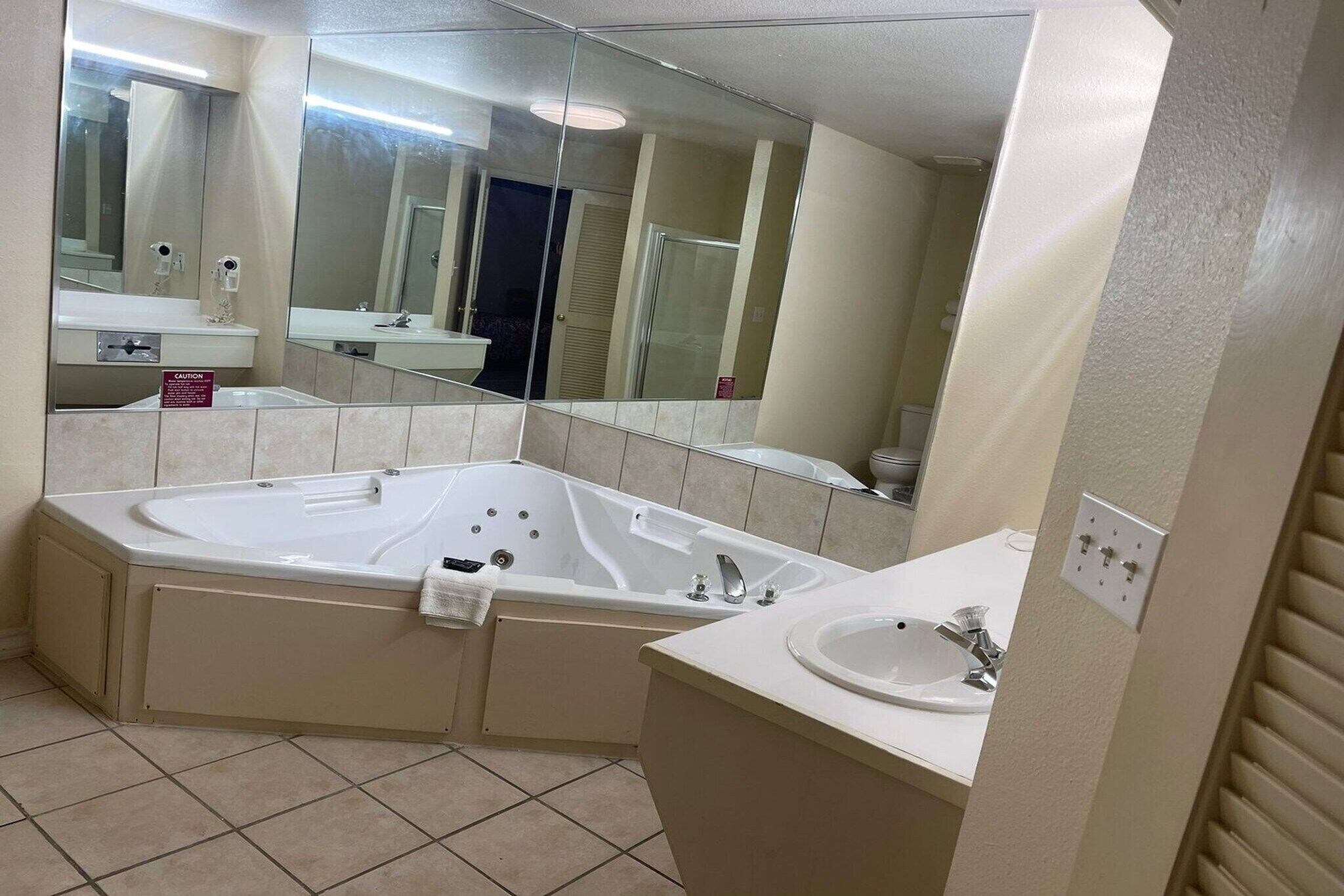 Un baño con una bañera grande, un lavabo y un espejo.