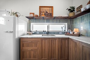 Una cocina moderna con armarios de madera, un refrigerador blanco, un ventanal grande y un salpicadero de azulejos.