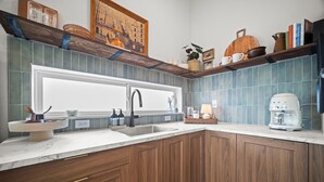 A kitchen with wooden cabinets, a white countertop, a sink, and a coffee maker.