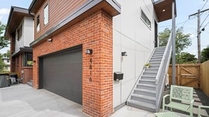 A modern house with a brick exterior, a garage, a staircase, and outdoor seating.