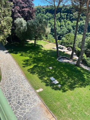A paved pathway leading to a grassy area with trees and a stone structure. - Apartment 'The Mill' in Historic Villa near Lake Como (Caslino D'erba)