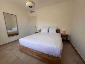 Ein Schlafzimmer mit einem hölzernen Bett, einem Nachttisch mit Lampe, einem Spiegel und einer an der Decke befestigten Überwachungskamera.