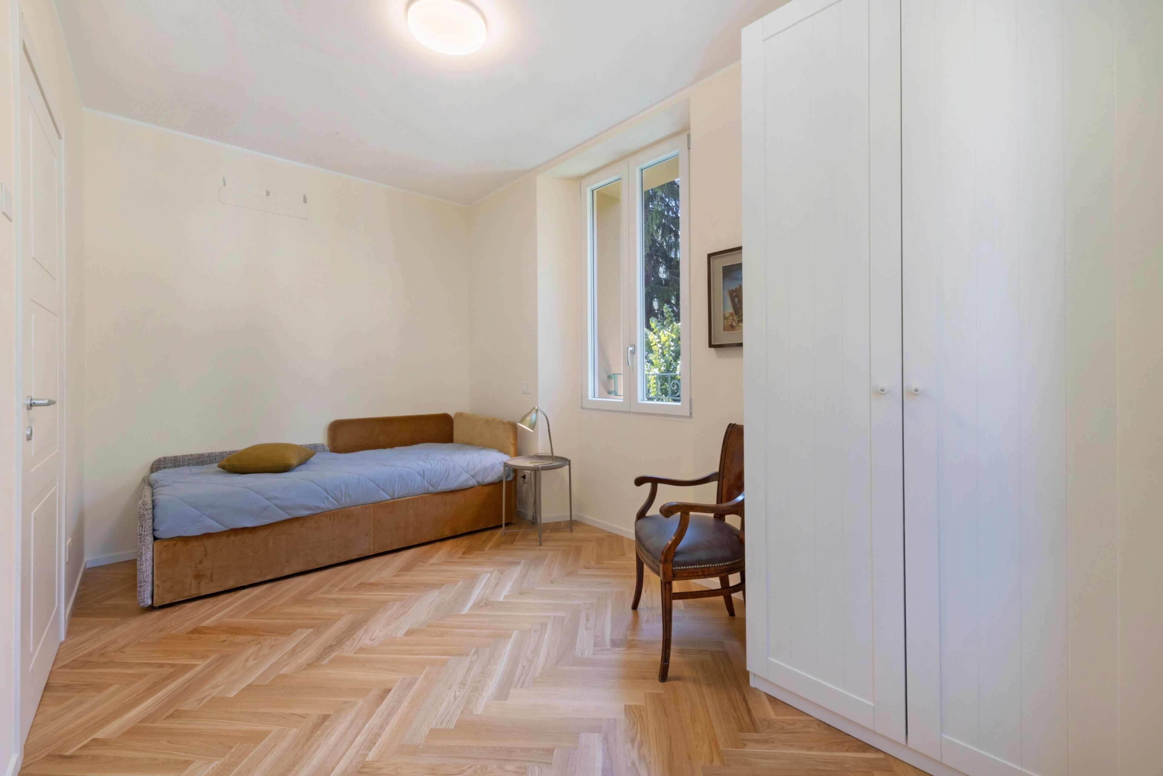 Ein Schlafzimmer mit einem Bett, einem Sessel, einem kleinen Tisch und einem Kleiderschrank.