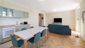 Una cocina moderna con una mesa de comedor y sillas, un sofá y una televisión.