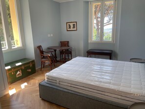 A room with a bed, a small table with chairs, a bench, and a green chest of drawers.