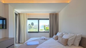 Una camera d'albergo con un letto, una televisione, una cassettiera e una finestra con tende.