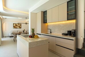 A modern kitchen with a marble countertop, a coffee machine, and a dining area with a sofa and chairs. - Green villa II, Stylish villa with pool near beaches in Rethymno (Rethymno, Pigi)