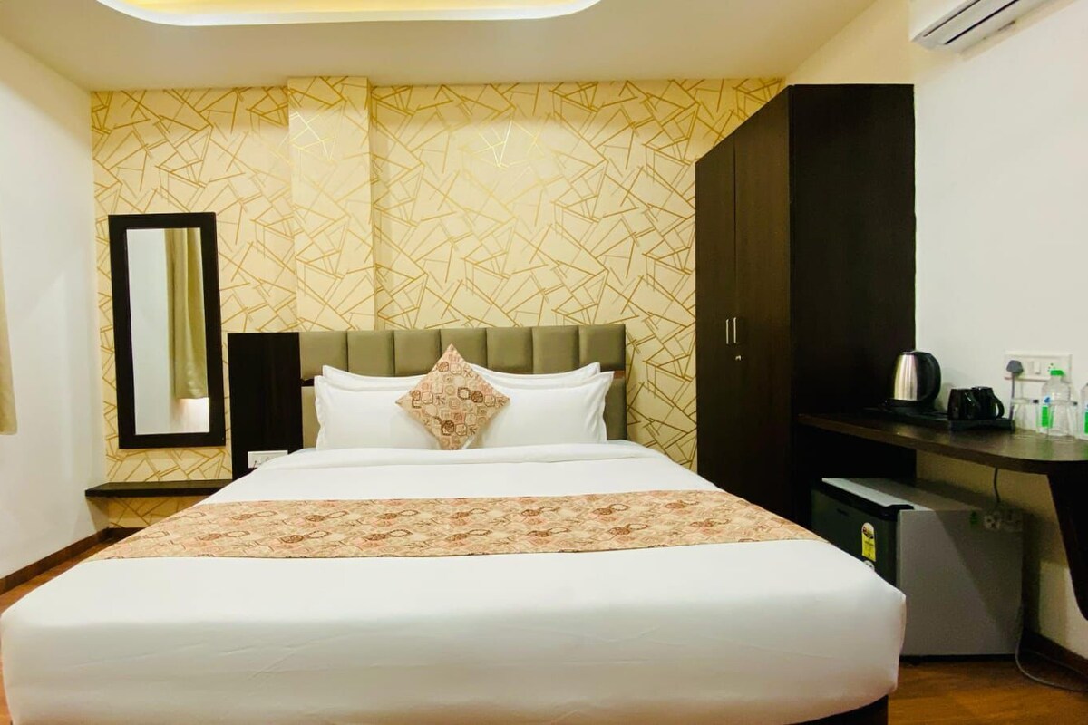Una habitación de hotel con cama, un escritorio con cafetera y un armario.
