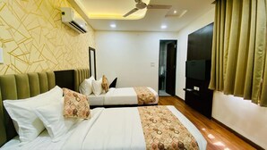 A hotel room with two beds, a ceiling fan, a TV, and a wardrobe. - Hotel Rove Inn (Indore)