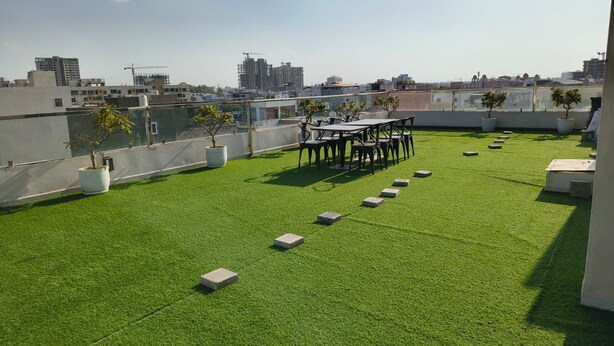 A rooftop terrace with artificial grass, potted plants, and a seating area. - Hotel Rove Inn (Indore)