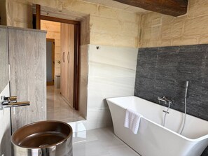 A modern bathroom with a freestanding bathtub, a wooden bucket, and a stone wall. - Girgor Farmhouse W/Pool&Jacuz byArcoCollection (St. Paul`s Bay)