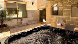 Een wellnessruimte met een jacuzzi, stenen muren en een zithoek met stoelen.