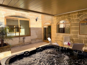 Ein Wellnessbereich mit Whirlpool, Steinwänden und einer Sitzecke mit Sesseln.