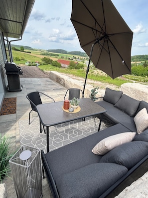 Eine Terrassengruppe mit Ecksofa, Tisch und Sonnenschirm.