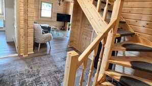 A wooden staircase with a handrail leading to an upper level. A flat-screen TV is mounted on the wall in the background.