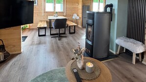 A wooden cabin interior with a dining area, a fireplace, a TV, and a cozy seating area.