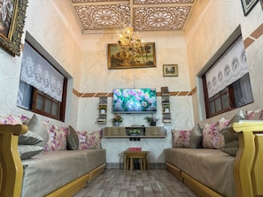 Una sala de estar con dos sofás, un televisor, estanterías decorativas y una araña.