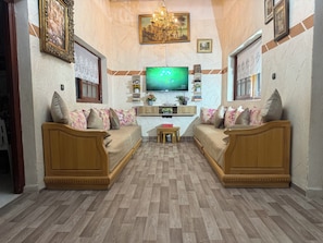 Ein Wohnzimmer mit zwei Sofas, einem Fernseher, einer Kristallleuchtre und einem Kamin.