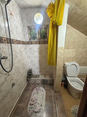 Ein Badezimmer mit Dusche, Toilette und einem kleinen Fenster.