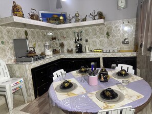 Una cocina con una mesa de comedor dispuesta para cuatro personas, una estufa y diversos electrodomésticos.
