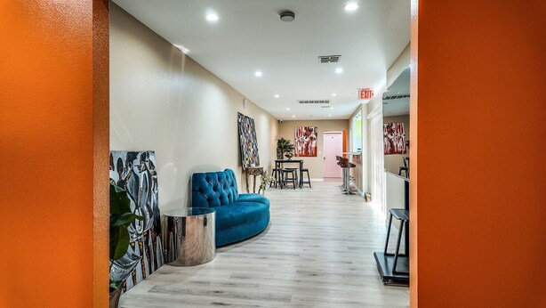 A hallway with a blue sofa, a small table, and chairs, and a door in the distance. - @ View Suite with private entrance, Lounge and sofa bed and bar. (Los Angeles)