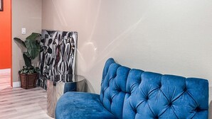 A curved blue sofa in a modern room with a light wooden floor and a large abstract painting on the wall. - @ View Suite with private entrance, Lounge and sofa bed and bar. (Los Angeles)