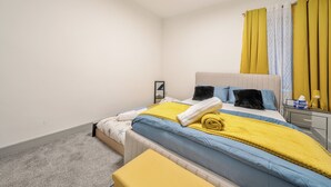 A bedroom with a bed, bedside table, and a mirror.