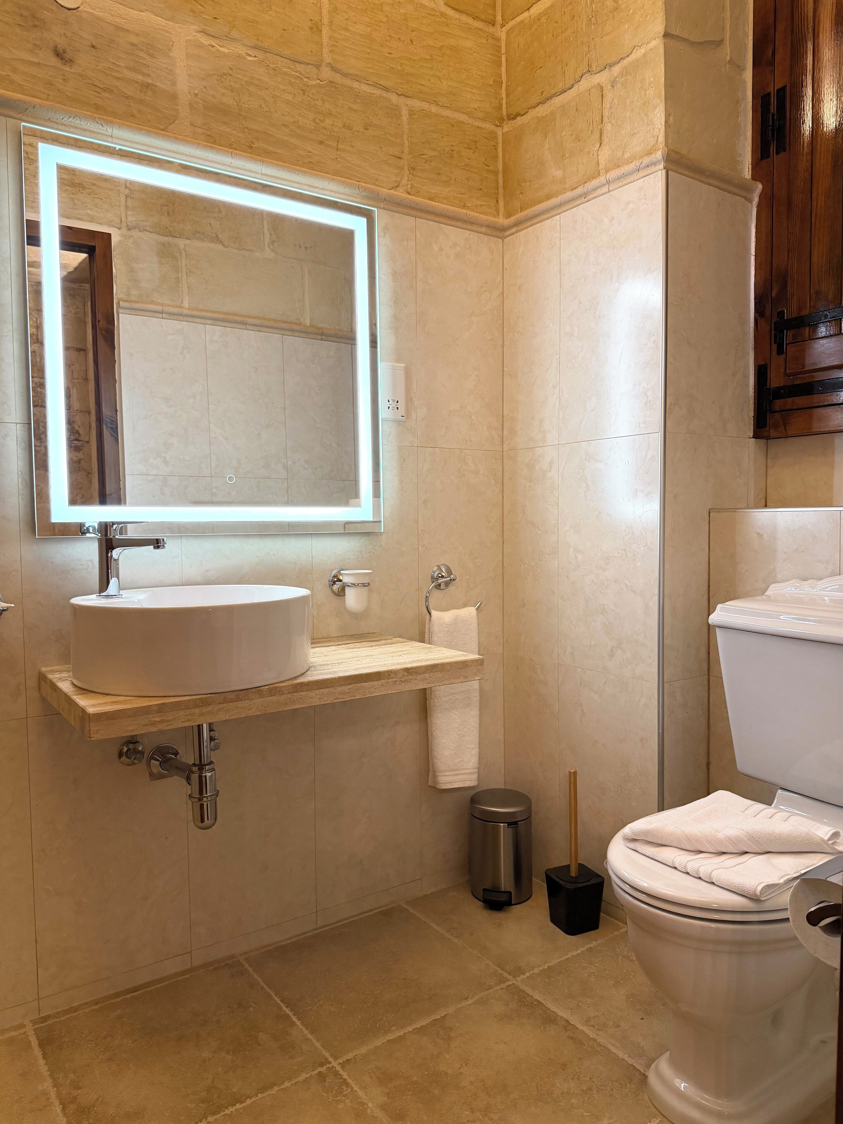 A bathroom with a white sink, mirror, and toilet.